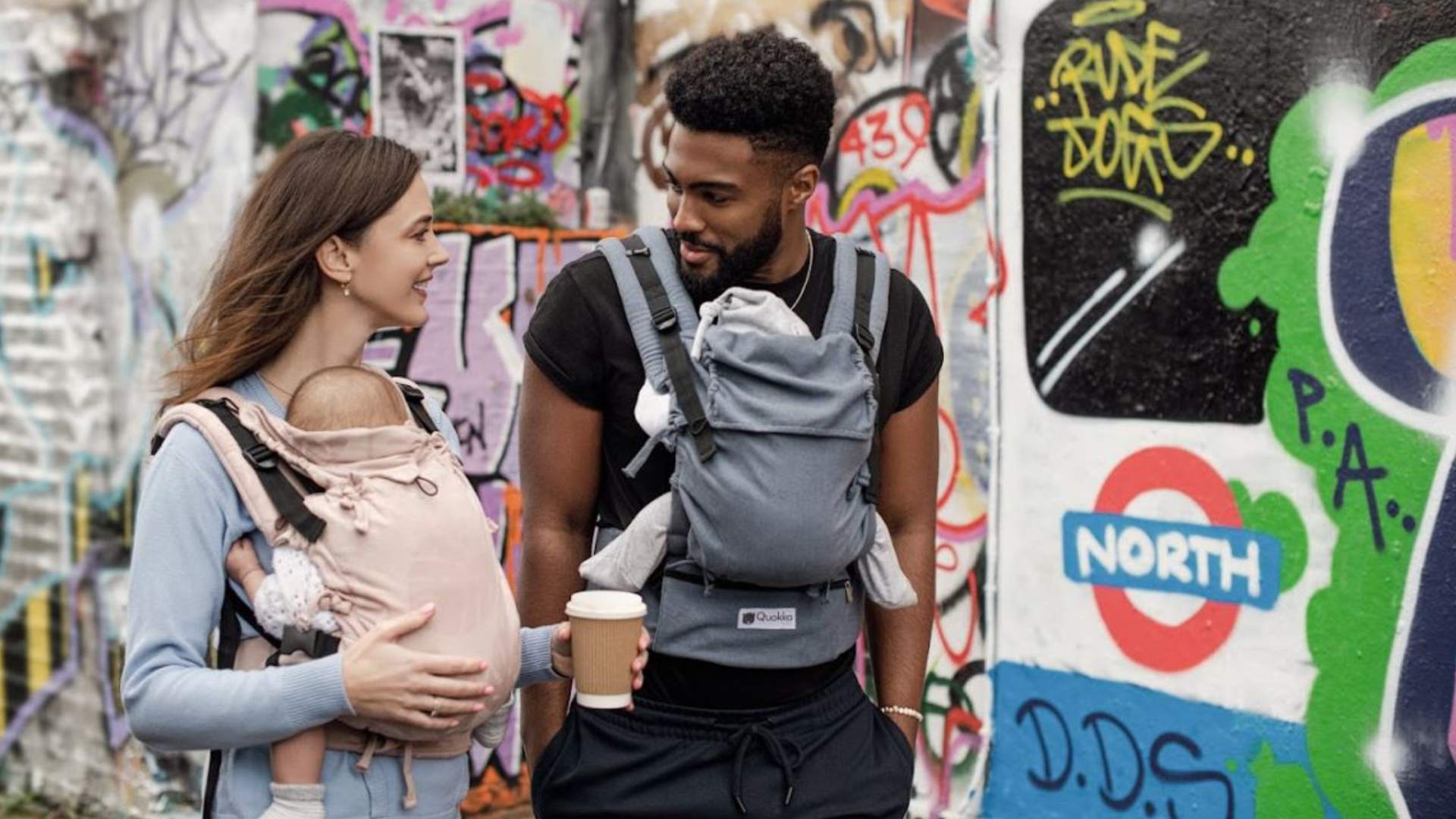 mochilas portabebes ergonomicas y evolutivas en accion con dos padres porteando a bebes de diferentes edades